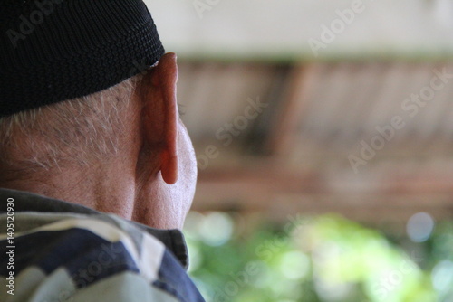 A person's ear and the side of their head, wearing a dark cap. Focus on hearing and the human profile