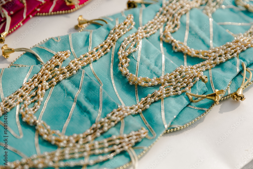 Fototapeta premium Close-up of turquoise and gold beaded decorative fabric, intricate detail, bright lighting.