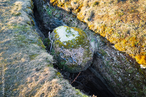 Unique view from Kostivere, Estonia: Giant boulder stuck in a narrow karst crevasse above the underground river. photo