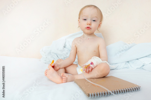 Obraz na płótnie 1,5 years old toddler girl painting or drawing by using color pencil at the hospital,Sick babysit on patien bed relax by painted on the sketch book. The concept of sublimation, art against pain and w salonie
