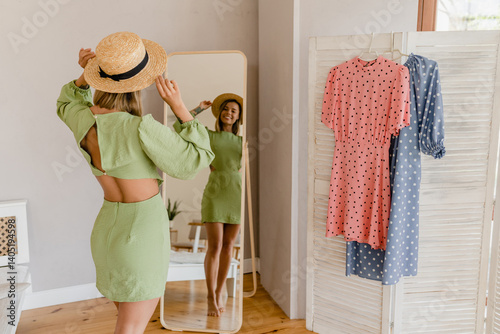 young pretty woman in green dress trying on style trend dress looking in mirror