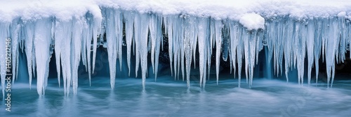 Frozen landscape featuring large icicles hanging over flowing water currents