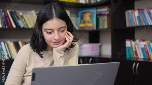 Teenage schoolgirl working on laptop in library