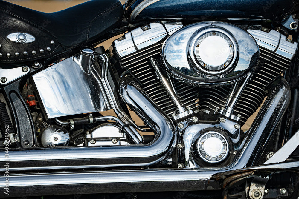 Motorblock und Auspuff einer legendären Motorradmarke glänzen im Sonnenschein.