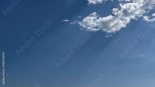Fototapeta Naklejka Na Ścianę i Meble -  A few bright clouds scatter the sun's rays across the deep blue sky, creating a peaceful and atmospheric scene.