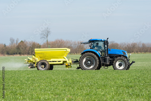 Tractor with fertiliser spreader in the grain field