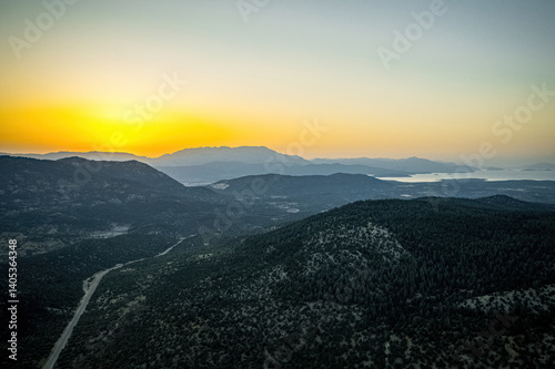 Obraz na płótnie Winding asphalt mountain road with green forest area surrounded by mountainous trees on both sides in sunset landscape. Drone footage. w salonie