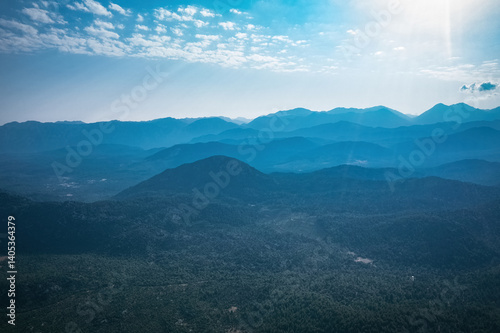 Magnificent nature with mountains and forests. Beautiful sunny valley with blue sky in summer. Aerial view with drone.