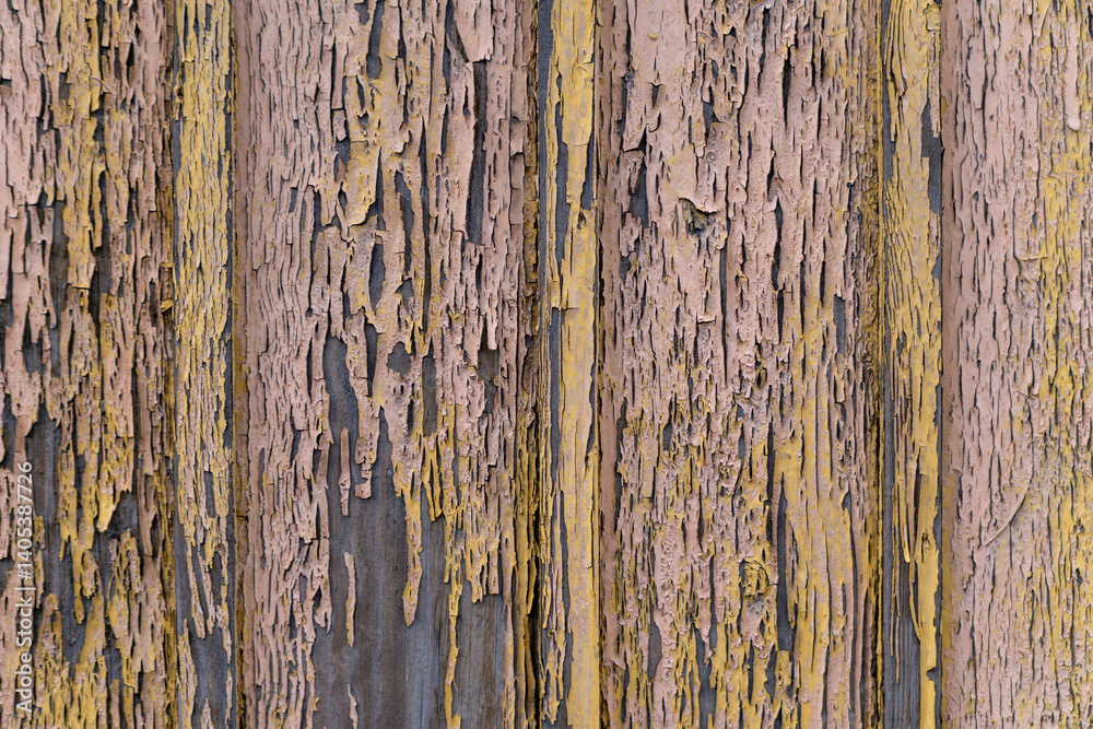 Obraz premium wooden boards covered with peeling paint in shades of yellow and brown. The texture of the paint and wood creates an interesting, abstract pattern, suggesting the passage of time and the natural aging