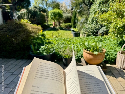 Fototapeta Naklejka Na Ścianę i Meble -  POV, Your point of view of reading a book while wind blows the page with sunny green grass garden in the background