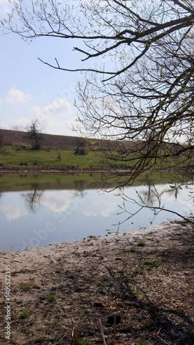 Beautiful spring landscape reflecting in a pond under a cloudy sky