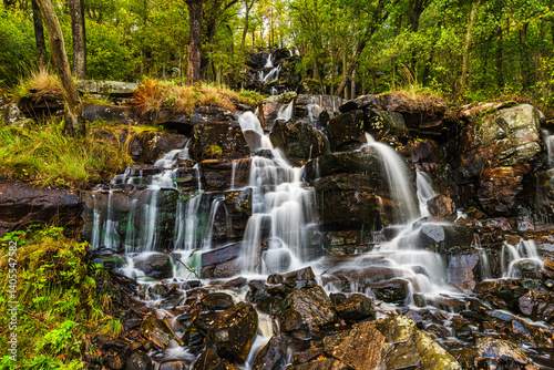 Beautiful cascading waterfall in Sweden surrounded by lush greenery and rugged rocks