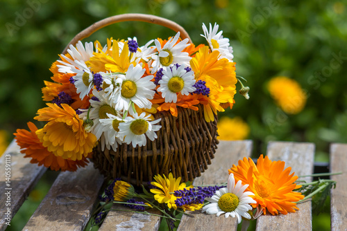 Obraz na płótnie Beautiful fresh summer flowers in wicker basket on table against blurred floral background w salonie