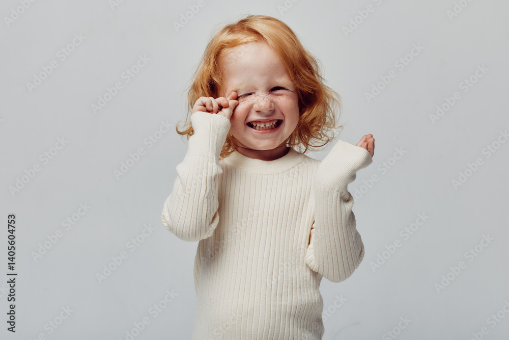 Little girl in white sweater covering her eyes with hands in a playful hideandseek game