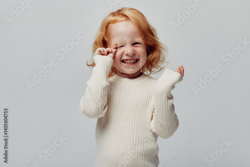 Obraz na płótnie Little girl in white sweater covering her eyes with hands in a playful hideandseek game w salonie