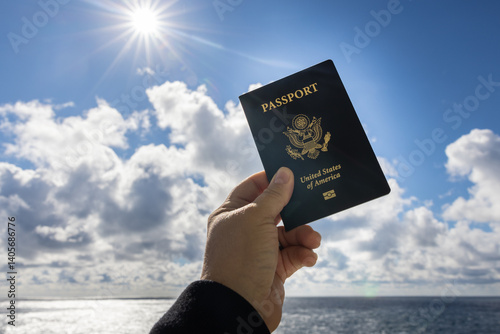 Photograph of hand holding up passport on bright beautiful day fluffy white clouds and blue sky.