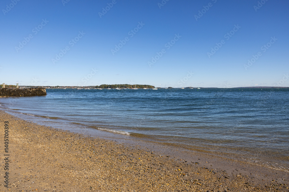 Photograph of shoreline on beautiful bright sunny day with gravel sandy beach and calm flowing water. Photograph of shoreline on beautiful bright sunny day with gravel sandy beach and calm flowing water.