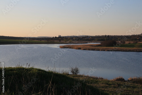 Obraz na płótnie A body of water with grass and trees around it w salonie