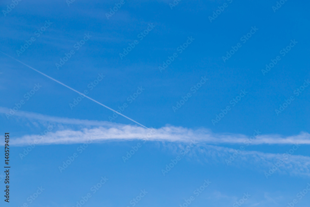 Blue Sky with Wispy Clouds and Contrasting Contrail Lines Visible Blue Sky with Wispy Clouds and Contrasting Contrail Lines Visible