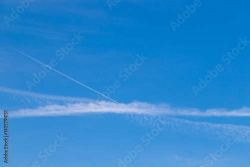 Blue Sky with Wispy Clouds and Contrasting Contrail Lines Visible