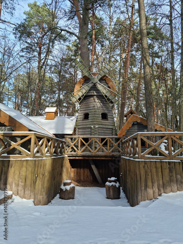 Tiny dwarf village hidden in the forest. Snow covered elf houses. Whimsical travel place. Windmill at the thematic park.