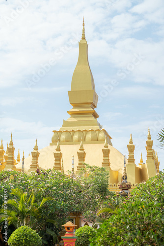 That Luang Stupa in Vientiane, Laos, shining brightly under a clear blue sky during the Lao New Year festival. The golden landmark represents national pride, peace, and spiritual heritage