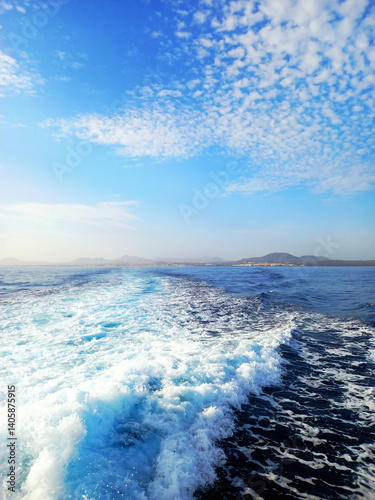Foam trail in the sea. Boat wake in the sea. Ocean waves and blue sky with white clouds. Seascapes and ocean foam. Relaxation and seabed.