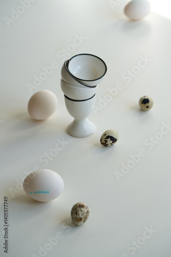Chicken and quail eggs on a white table, modern Easter-themed still life.