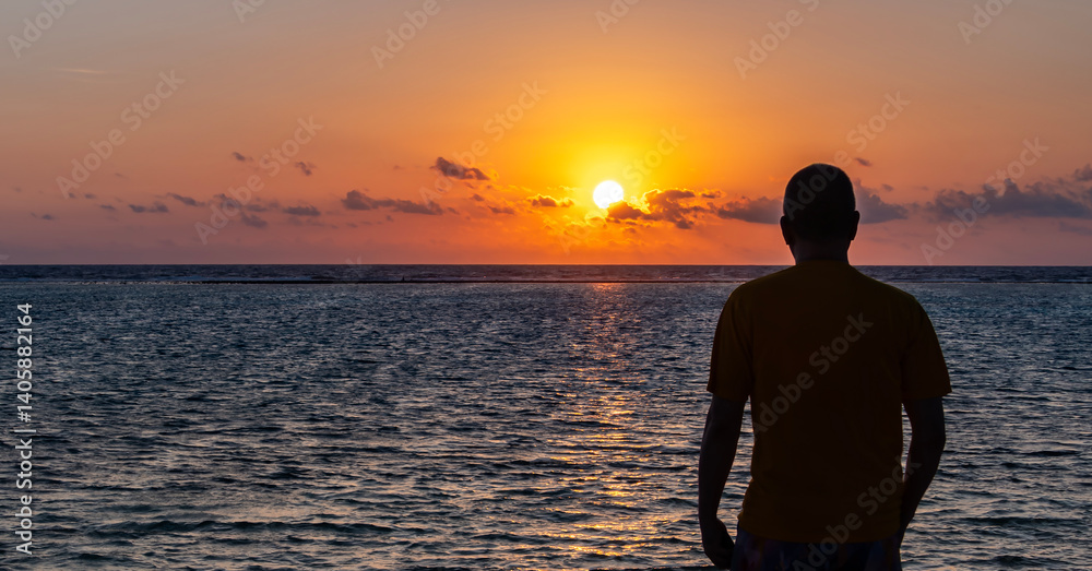 Silhouette of a Man looking at a Beautiful Sunrise on a Tropical Beach