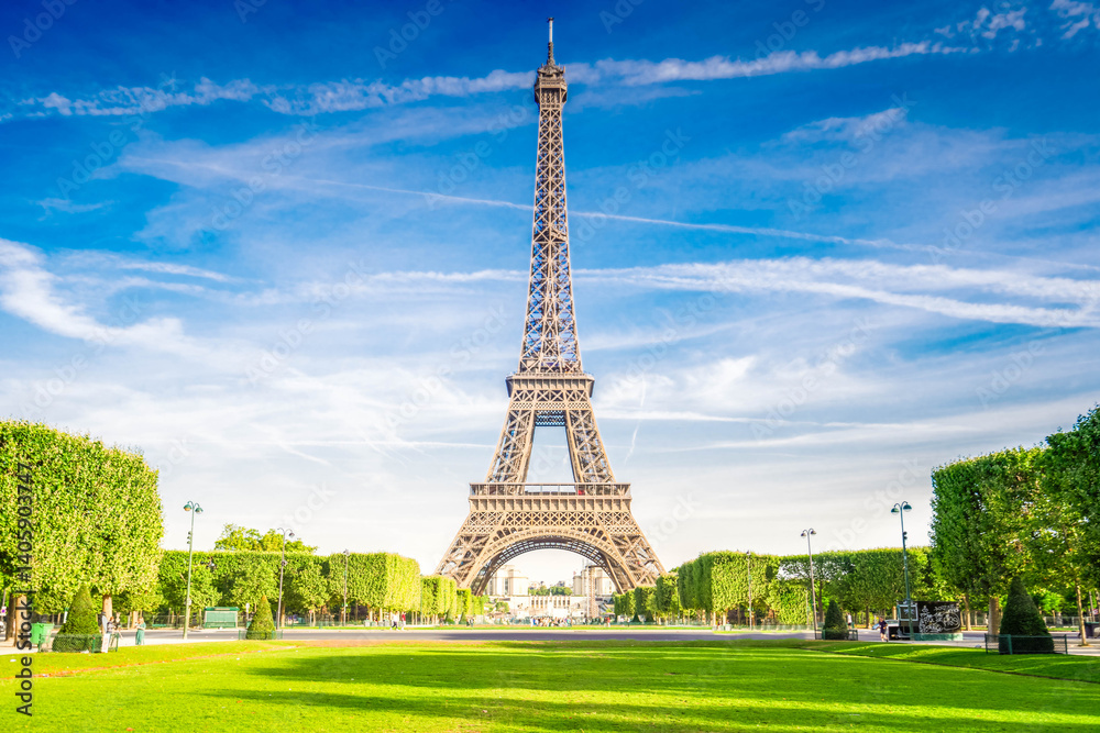 Fototapeta premium Paris Eiffel Tower over green grass lane in Paris, France. Eiffel Tower is one of the most iconic landmarks of Paris.