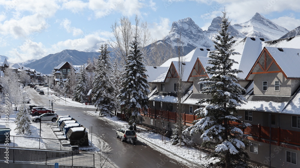 Fototapeta premium Snowy Street Scene in Canmore, Alberta, with Mountain Peaks in the Background 