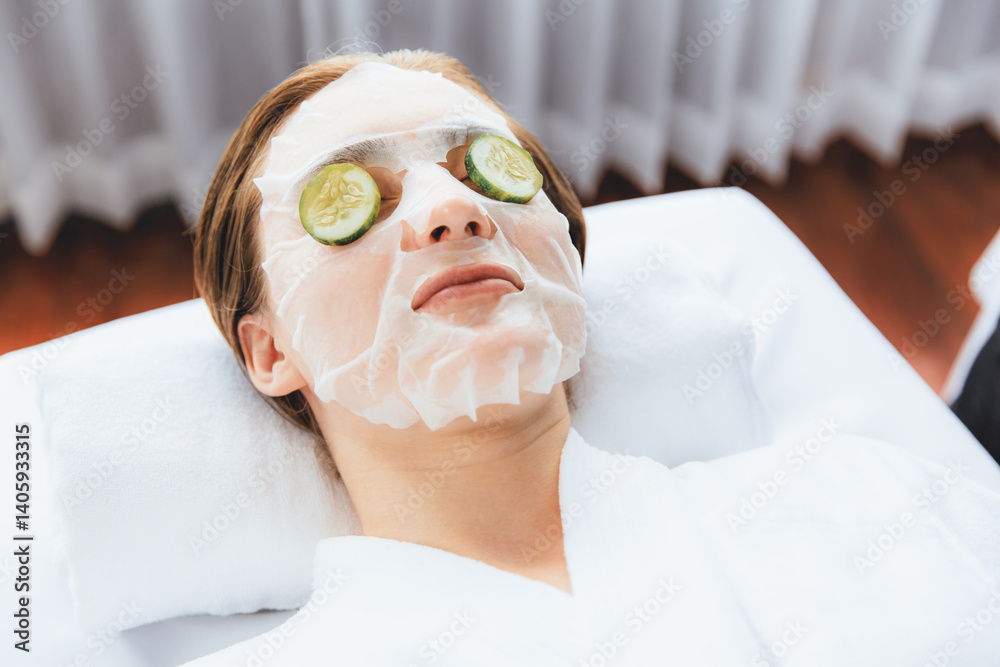 Serene daylight ambiance of spa salon, woman customer indulges in rejuvenating with luxurious cucumber facial mask. Facial skincare treatment and beauty care concept. Quiescent