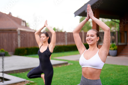 women practicing yoga outdoors in lush garden setting, showcasing wellness and mindfulness. focus on fitness, relaxation, and serenity in natural surroundings for healthy lifestyle inspiration photo