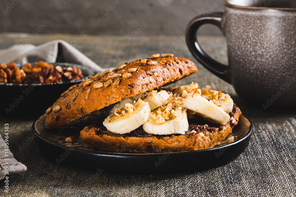 Close up of toast rye bread with chocolate and banana on a plate on the table