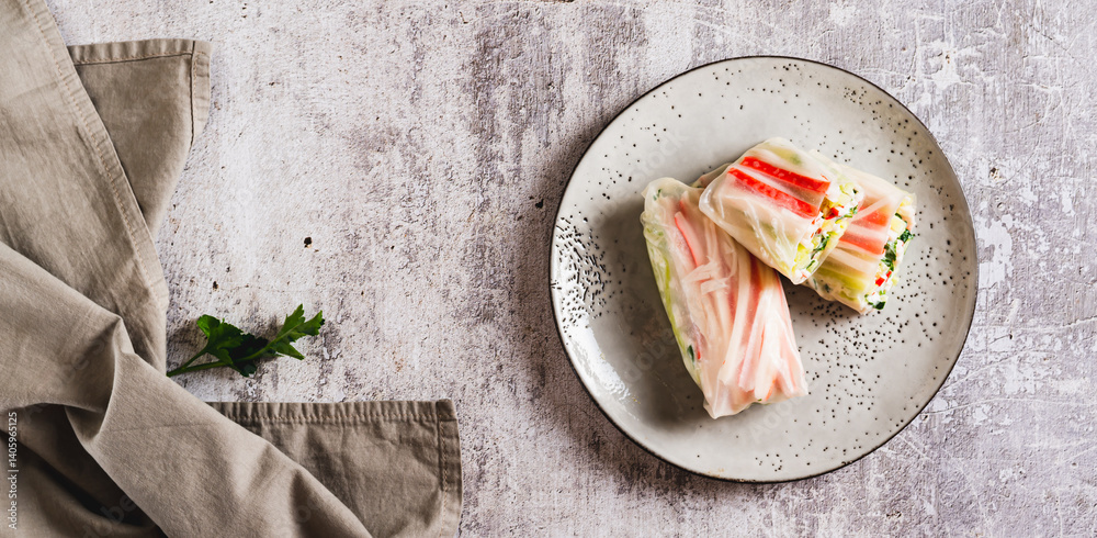 Spring rolls with crab meat, cucumber and herbs on a plate on the table top view web banner