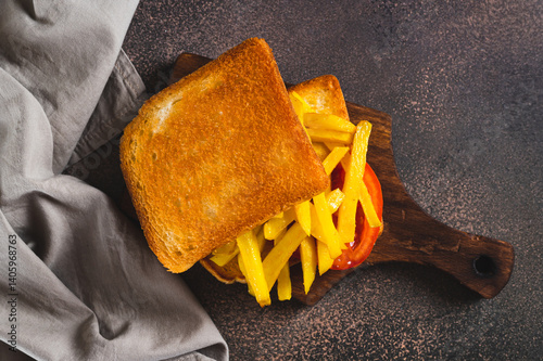 Obraz na płótnie Close up of fried toasts with french fries and tomato on a board on the table top view w salonie