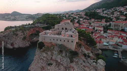 Beautiful and stunning aerial footage showcases a historic fort located on the Croatian coastline during sunset hours