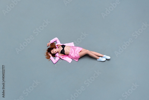 Obraz na plátne Woman in pink clothes lying down on a concrete floor, above view