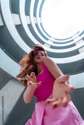 Woman in pink dancing, low angle view, in a spiral parking garage