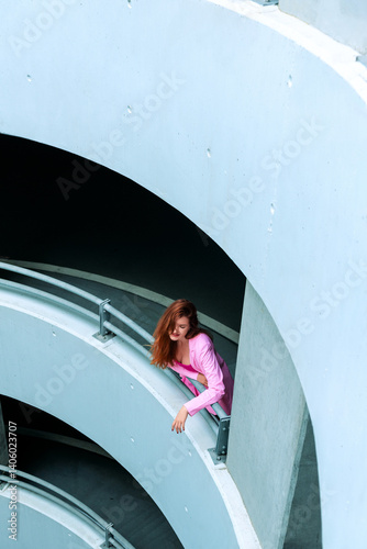 Young woman relaxing in a parking garage. Millennial woman wearing pink clothes