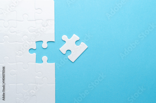 Concept for problem-solving, teamwork, solutions, or missing connections. White jigsaw puzzle on a vibrant blue background with one missing piece. Minimalist composition with copy space.