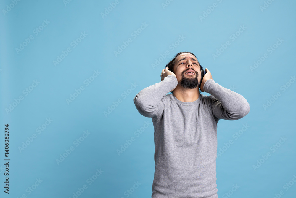 Confident man wearing wireless headphones and feeling the groovy music, enjoying a relaxing moment. Young adult shows audio enjoyment, modern gadgets and personal leisure activity. Confident man wearing wireless headphones and feeling the groovy music, enjoying a relaxing moment. Young adult shows audio enjoyment, modern gadgets and personal leisure activity.