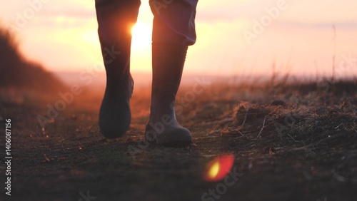 Foto A farmer in rubber boots and a tablet in his hands walks through the green field in rubber boots, the concept of farming business, view the planted shoots of crops, the harvest of eco-crops
