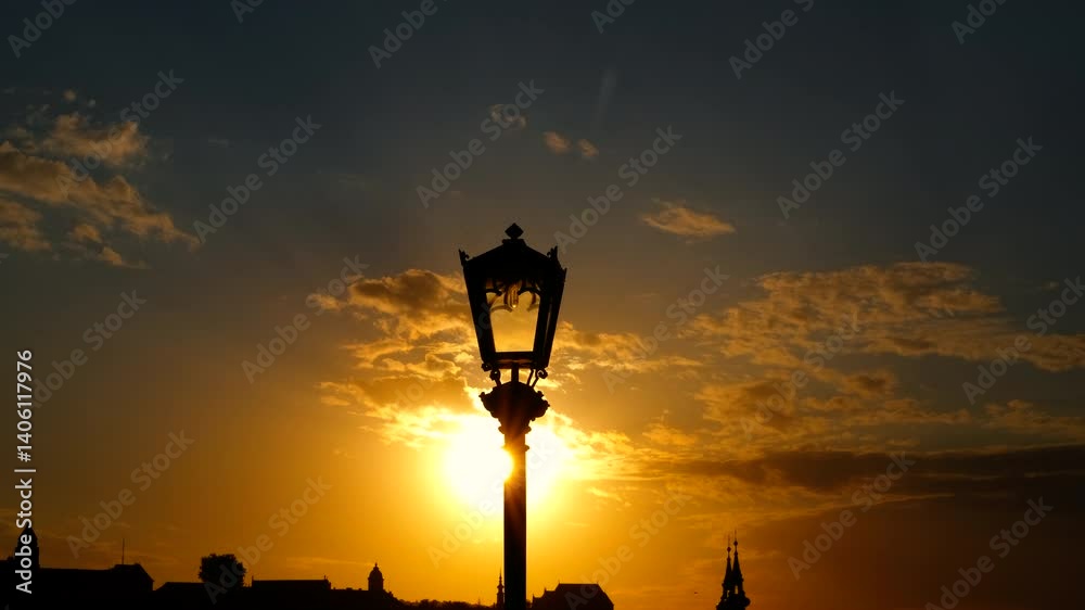 Sunset glowing behind a silhouetted lamppost. Stunning sunset casts orange and yellow hues across the sky, creating a beautiful backdrop behind the silhouette of a lamppost. Sunset glowing behind a silhouetted lamppost. Stunning sunset casts orange and yellow hues across the sky, creating a beautiful backdrop behind the silhouette of a lamppost.