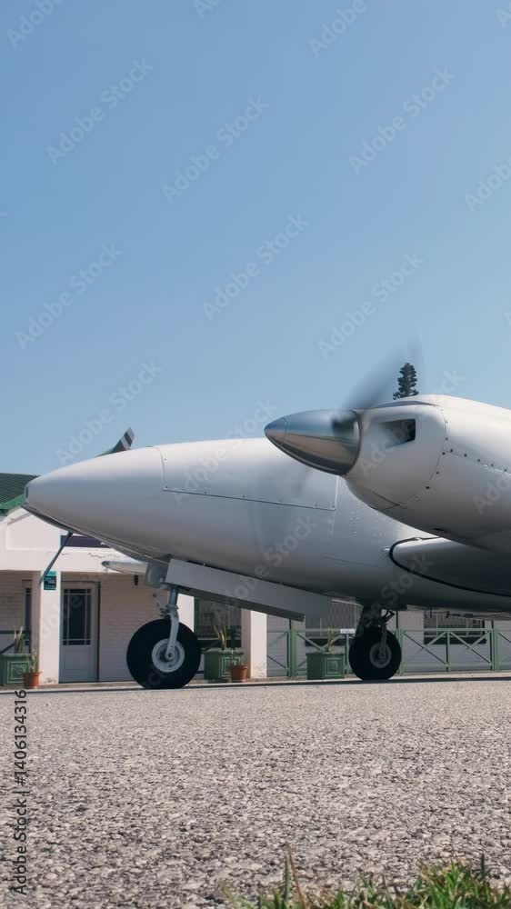 A twin turbo propeller white airplane standing on parking place running ups the engine.