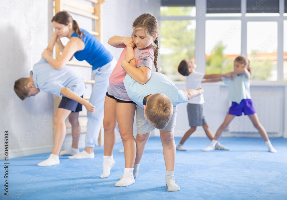 Obraz premium Young children, boy and girl, working in pair mastering new self-defense moves at gym