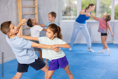 Boy and girl in gym perform basic elements of krav maga self-defense system. Preparation of athletes before competitions