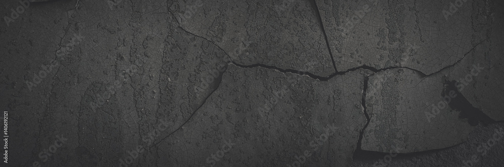 Dark wide panoramic background. Peeling paint on a concrete wall. Faded dark texture of old cracked flaking paint. Weathered rough painted surface with patterns of cracks. Shaded background for design