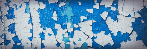 Obraz na płótnie Peeling paint on the wall. Panorama of a concrete wall with old cracked flaking paint. Weathered rough painted surface with patterns of cracks and peeling. Panoramic texture for background and design. w salonie