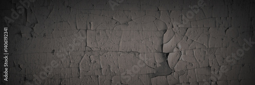 Dark wide panoramic background. Peeling paint on a concrete wall. Dark grunge texture of old cracked flaking paint. Weathered rough painted surface. Patterns of cracks. Darkness background for design.